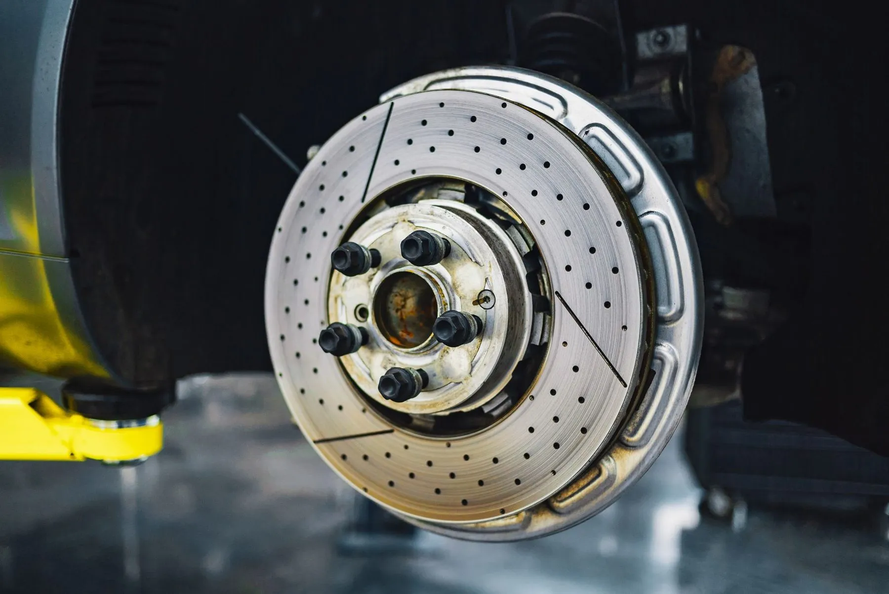 A drilled brake disc on a hub with the wheel removed