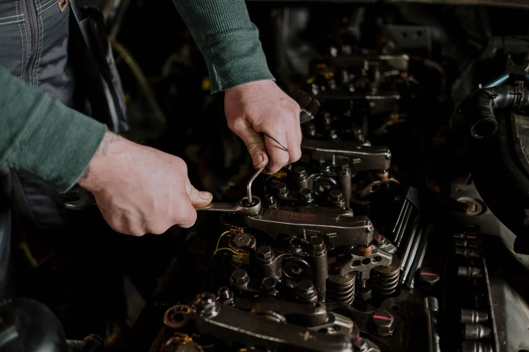 A technician's hands working on an engine with a spanner