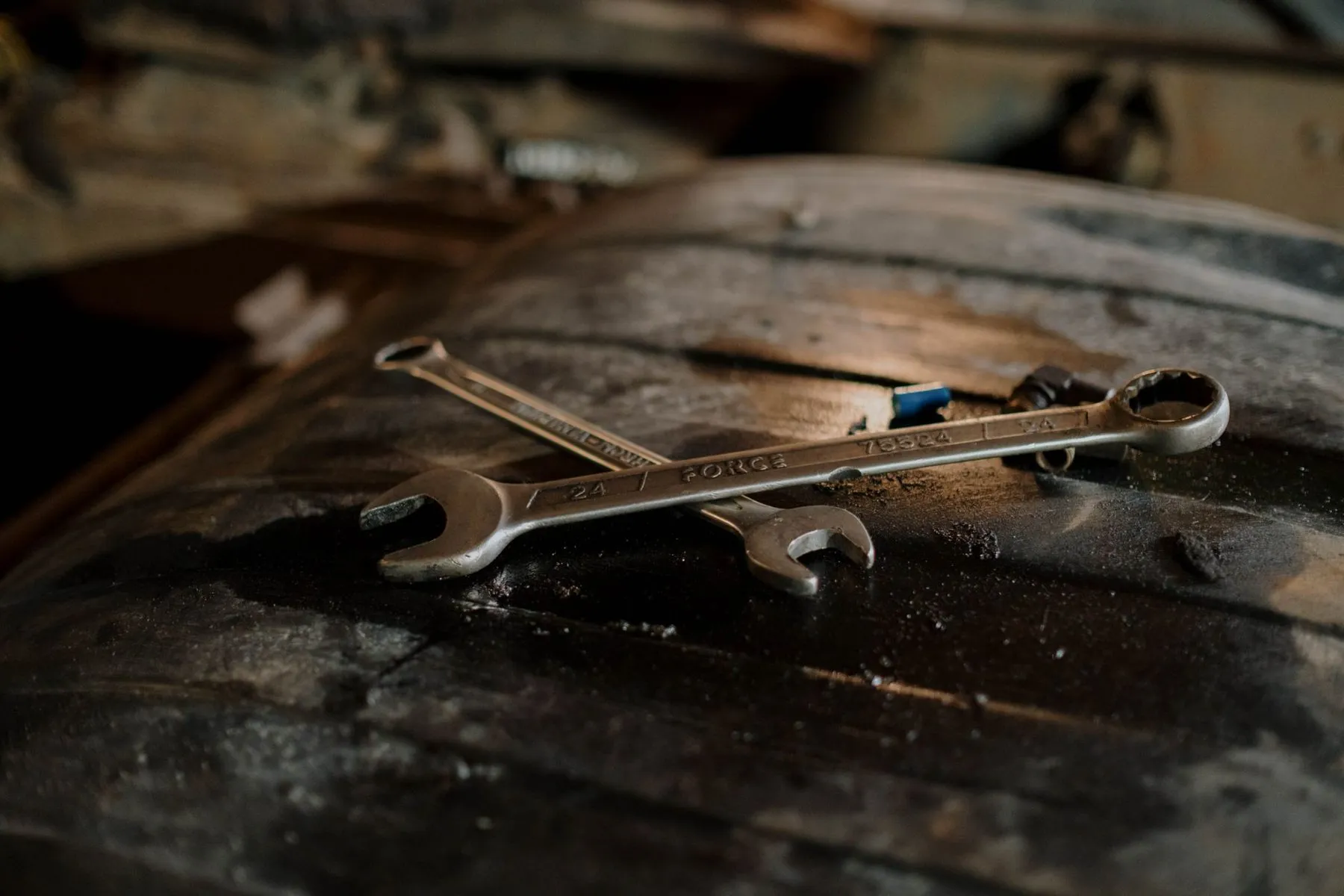 Two spanners resting on the tread of a worn tyre
