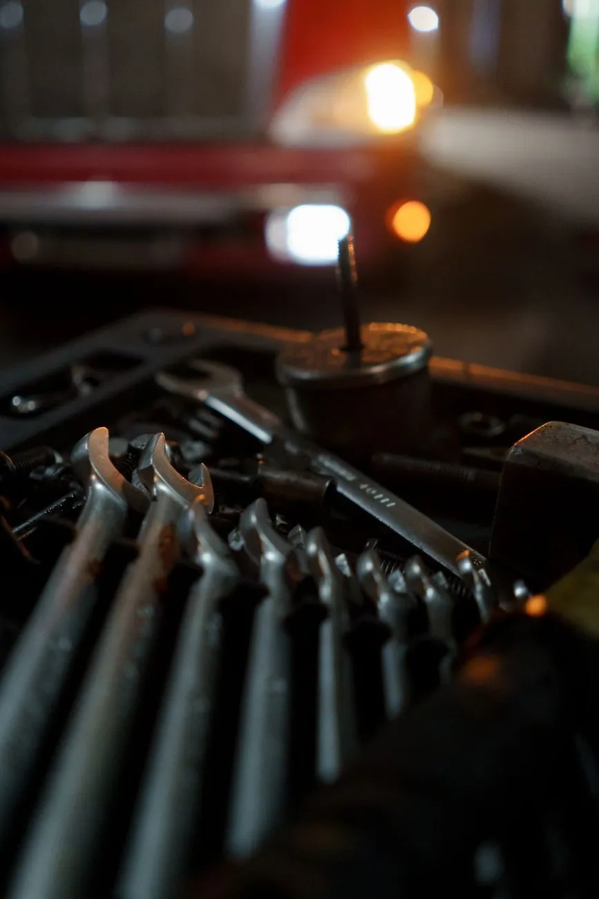 A tray of spanners and a torque tool on the bench, a car on the lift behind